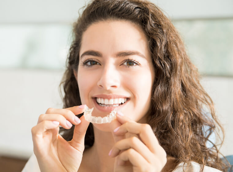 woman holding clear aligner