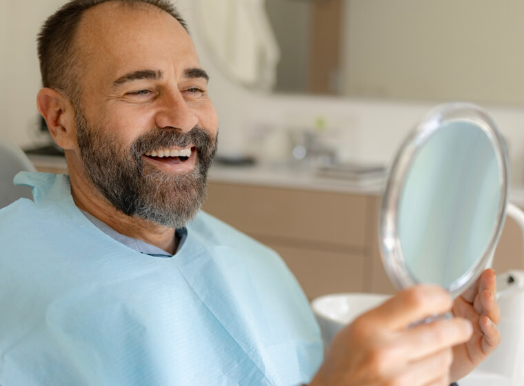 man smiling in mirror at the dentist